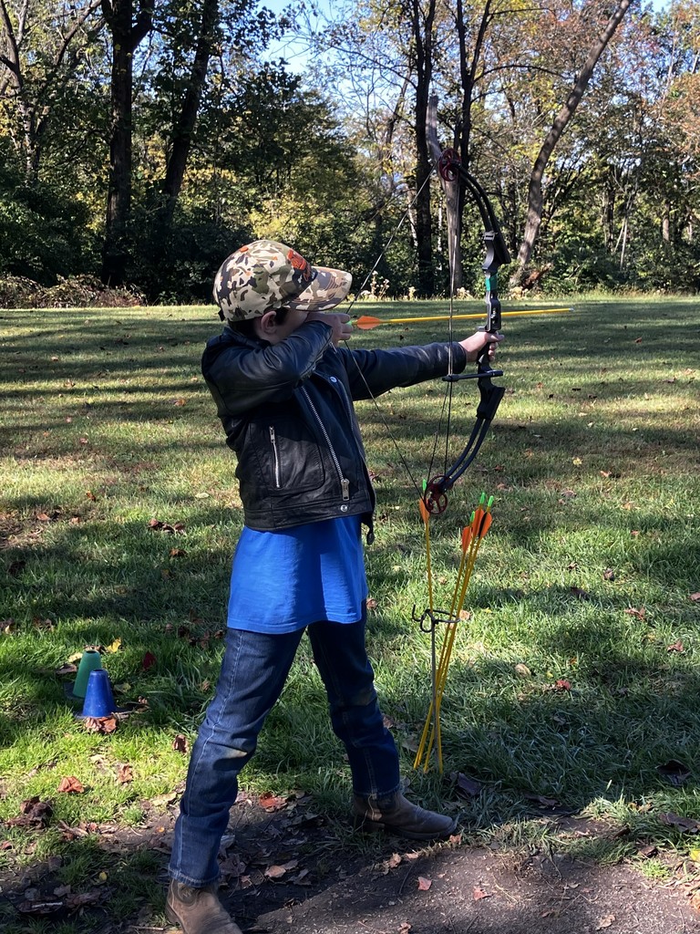 student shooting bow and arrow at a target