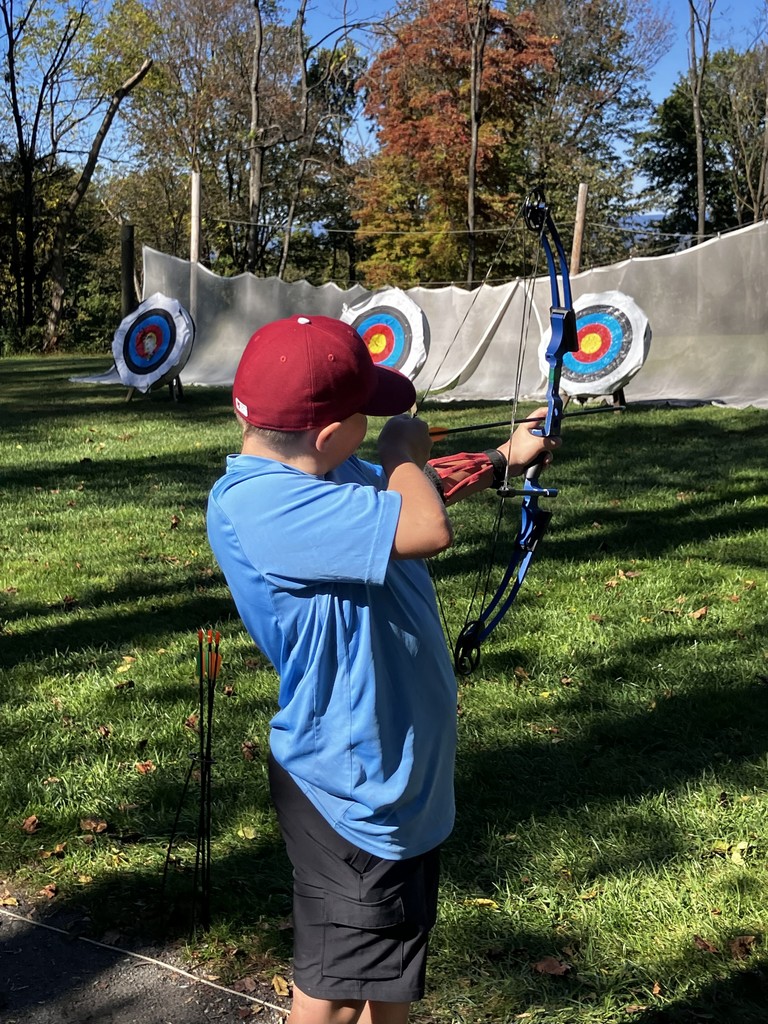 student shooting bow and arrow at a target