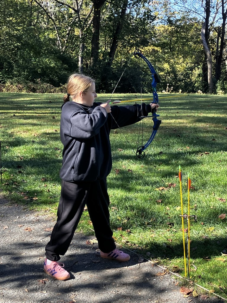 student shooting bow and arrow at a target
