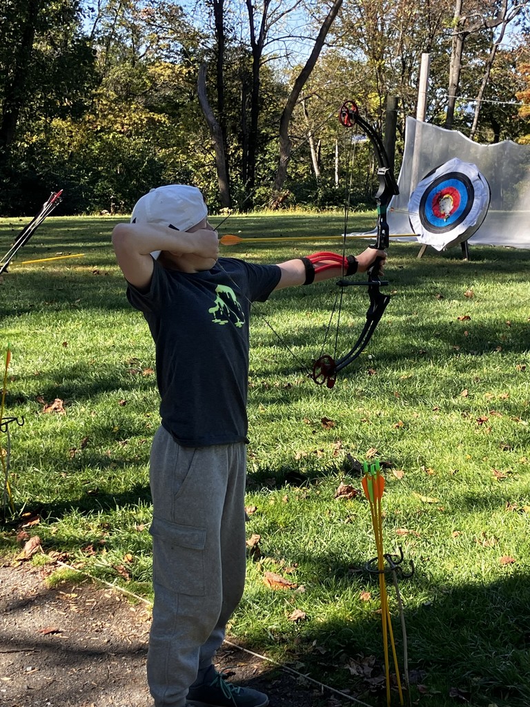 student shooting bow and arrow at a target