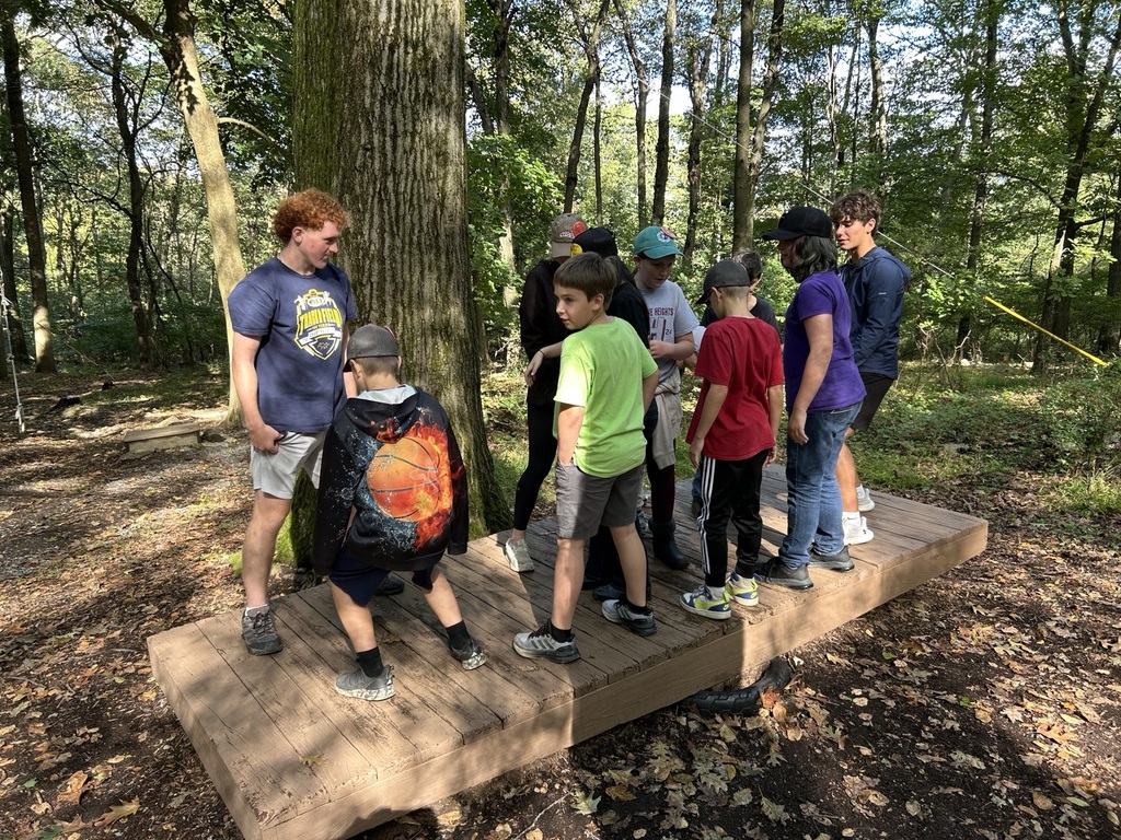 students stand on a platform trying to balnace