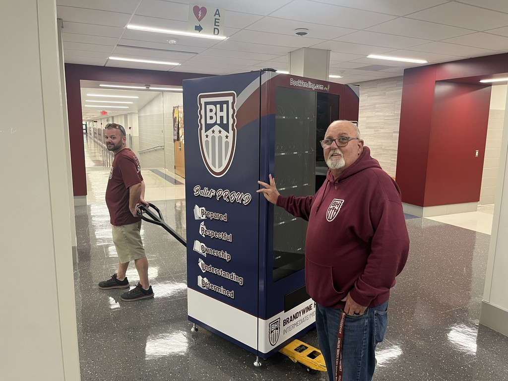 maintenance moving the book vending machine through the hallway
