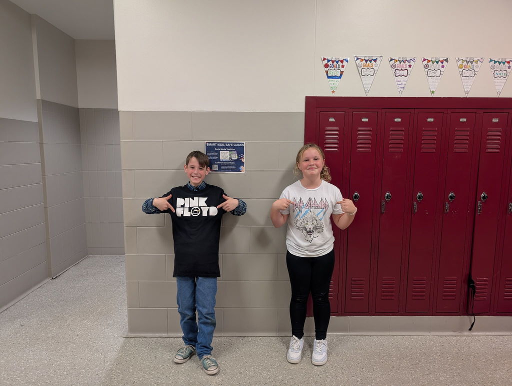 two students stand in band shirts