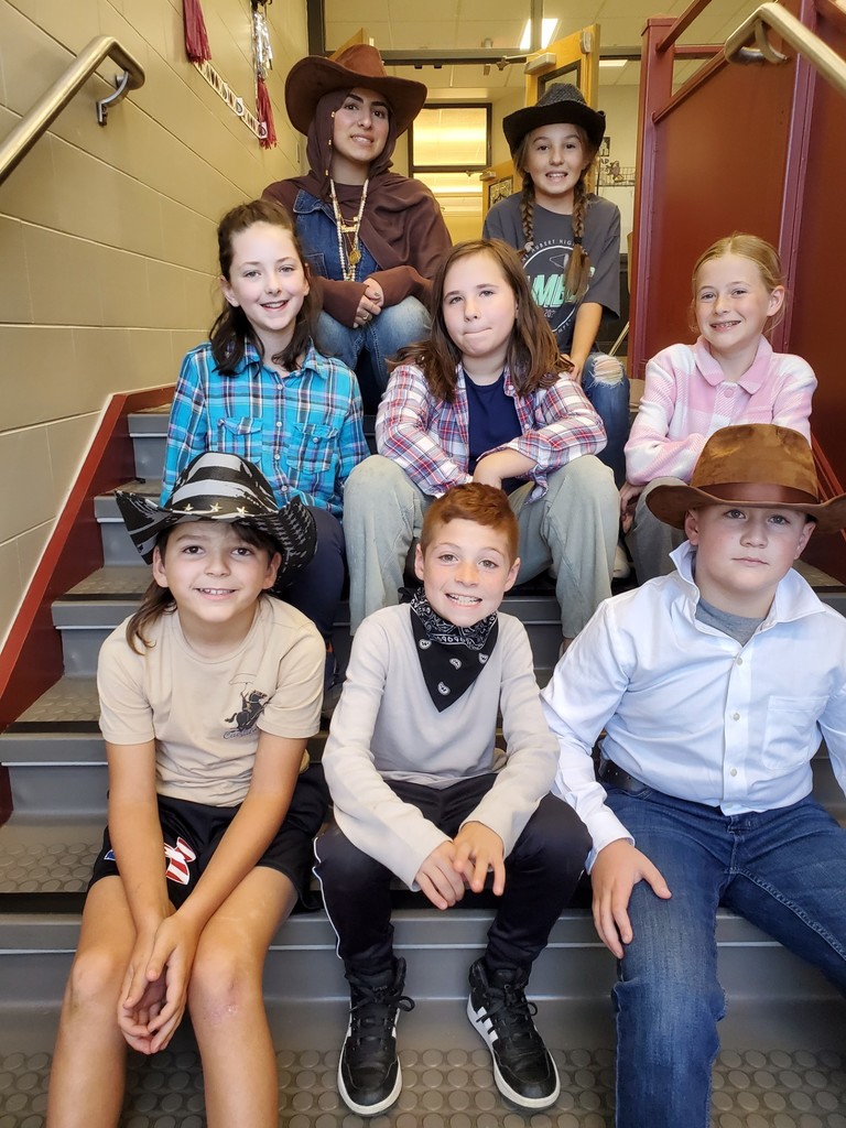 7 students and student teacher sit on steps in western gear
