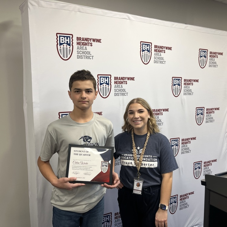 student with certificate stands with teacher