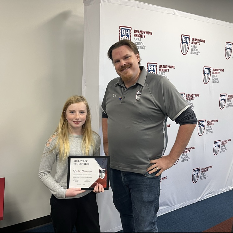 student with certificate stands with teacher