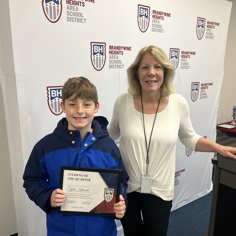 student with certificate stands with teacher