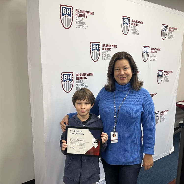 student with certificate stands with teacher