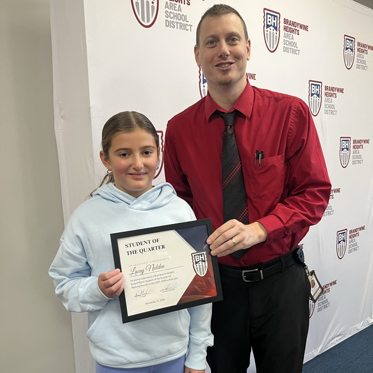 student with certificate stands with teacher