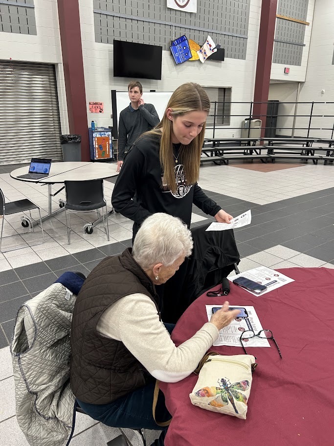 Student helps a senior citizen with her smartphone.