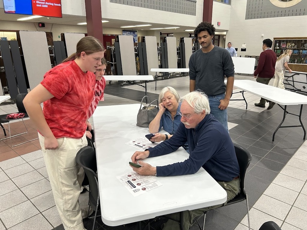 Students helps a senior citizen couple with their smartphones.