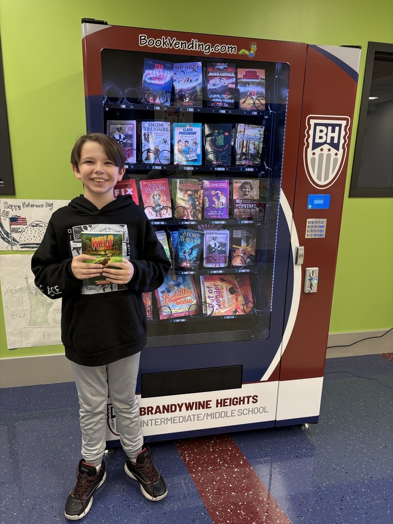student stands with book in front of book vending machine