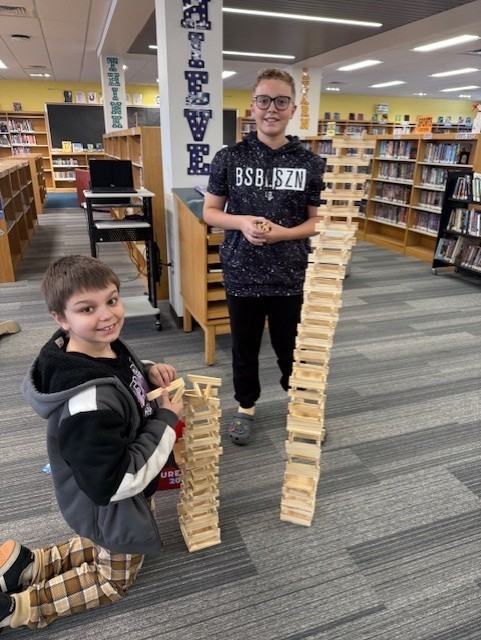 two students build a tower with wooden pieces