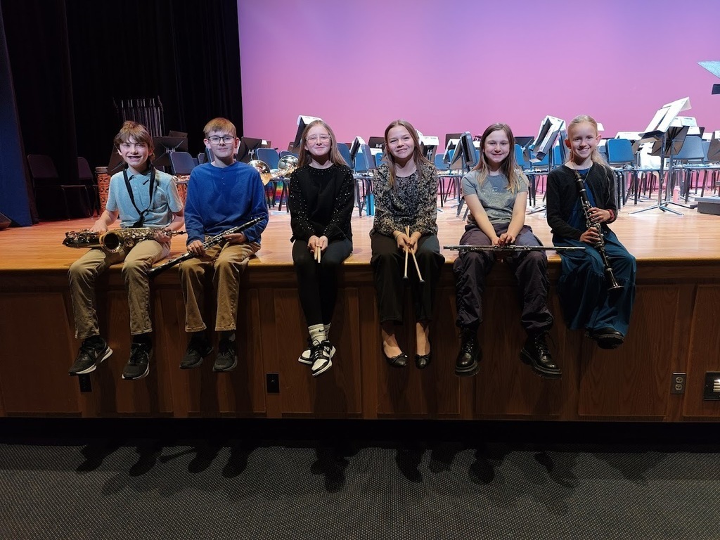Brandywine Heights students holding their instruments while sitting on the edge of a stage. 