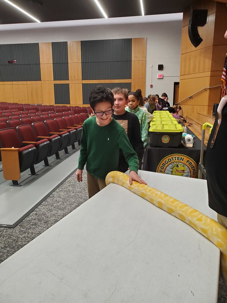 students petting a large yellow python on a table