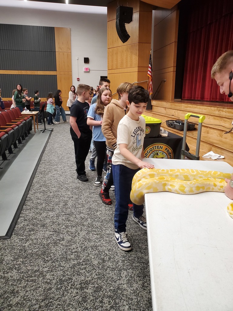 students petting a large yellow python on a table