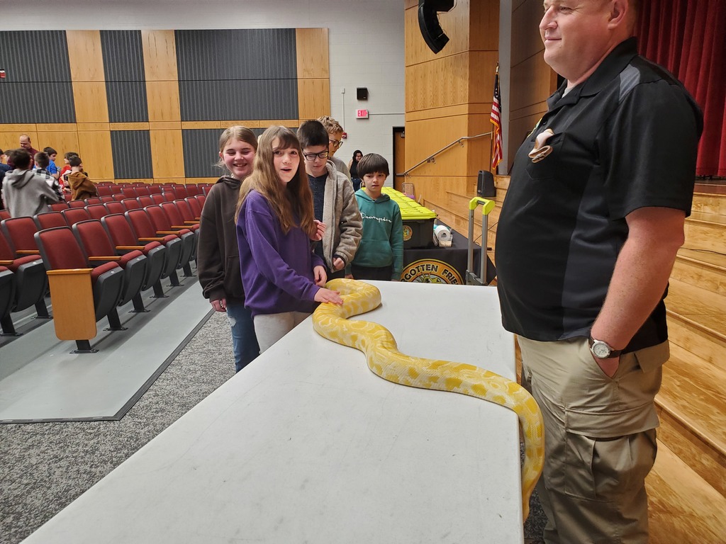 students petting a large yellow python on a table