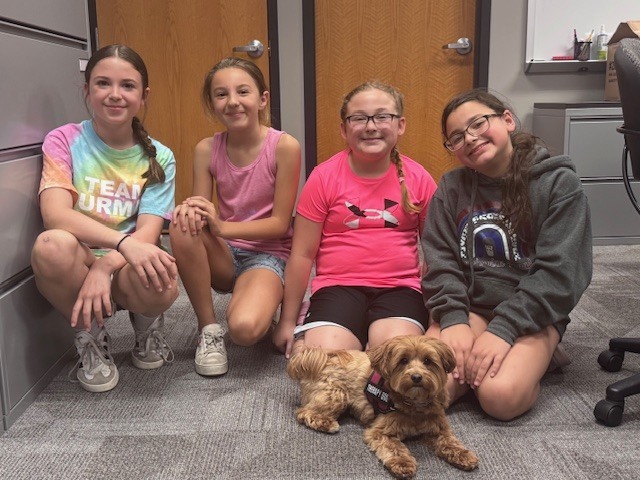 4 students sitting with a dog