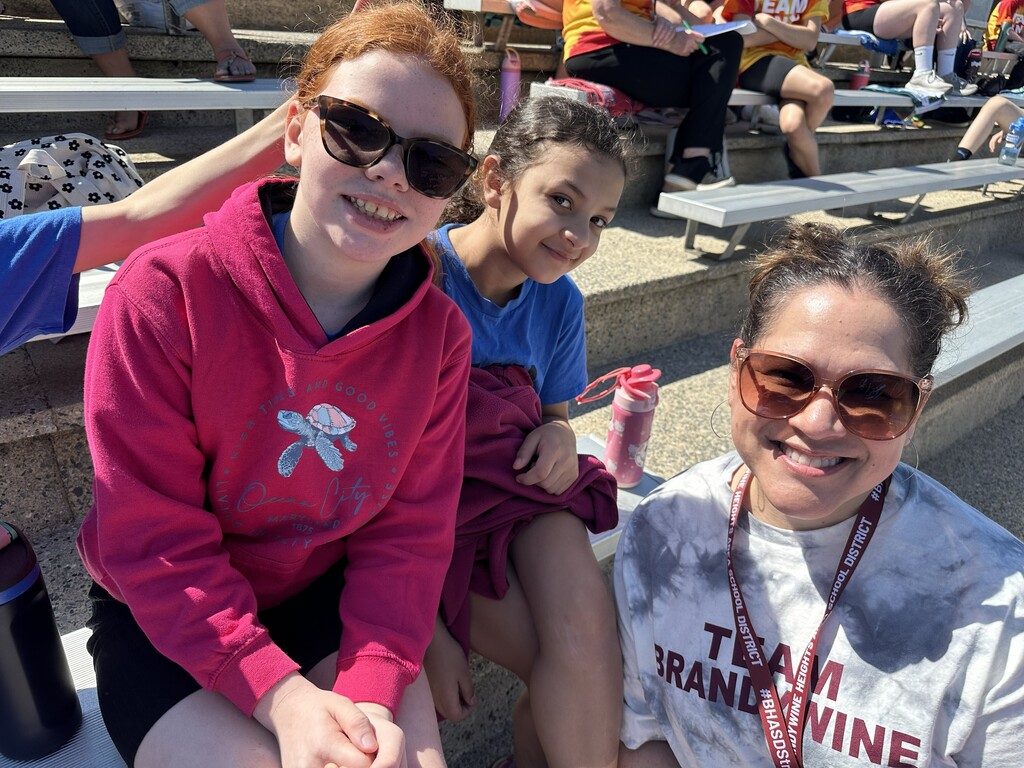 three people sitting on the bleachers smiling