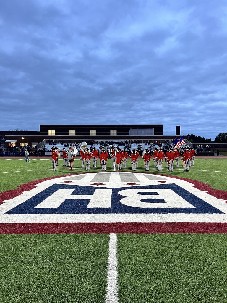 BHHS Marching Band performs on the field behind the school logo
