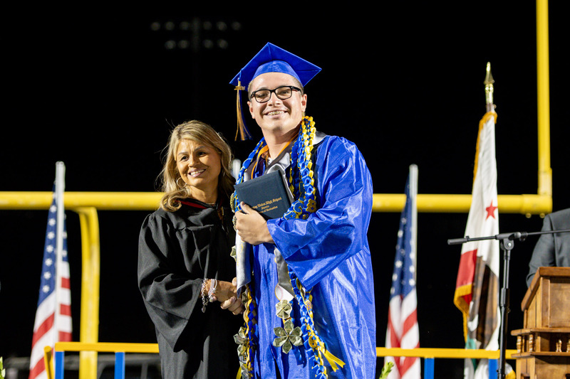 Student recieves diploma and shakes hand with Board member
