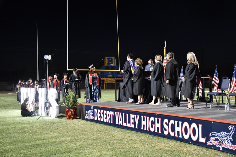 Graduates walk across graduation stage.