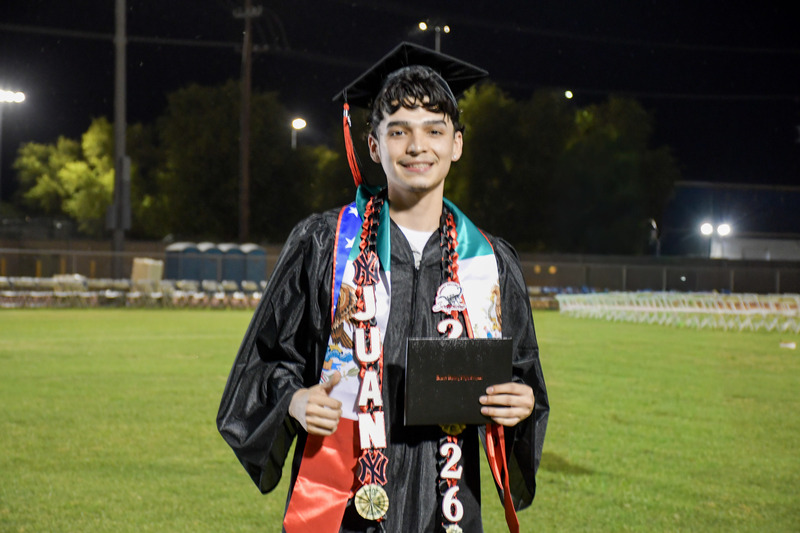 Graduates walk across graduation stage.