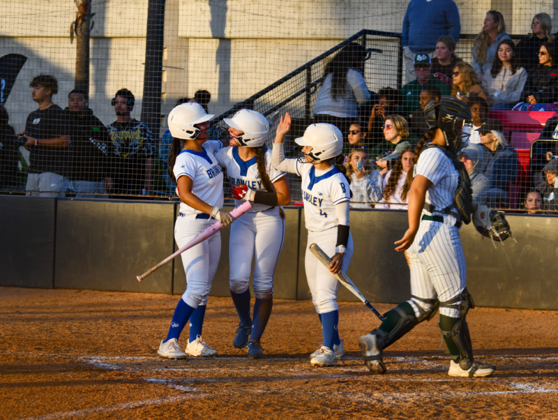 Softball player Ruiz celebrates at home plate after scoring run.