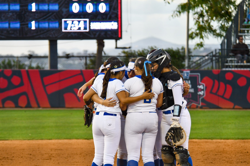 Players huddle up at the mound and embrace in group hug