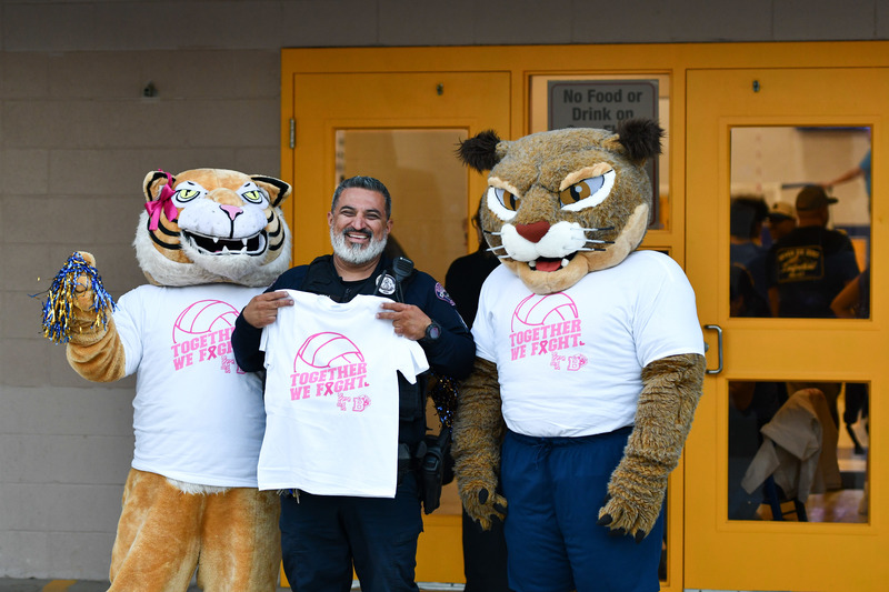 Wildcat mascots pose with officer ayala at pink out game
