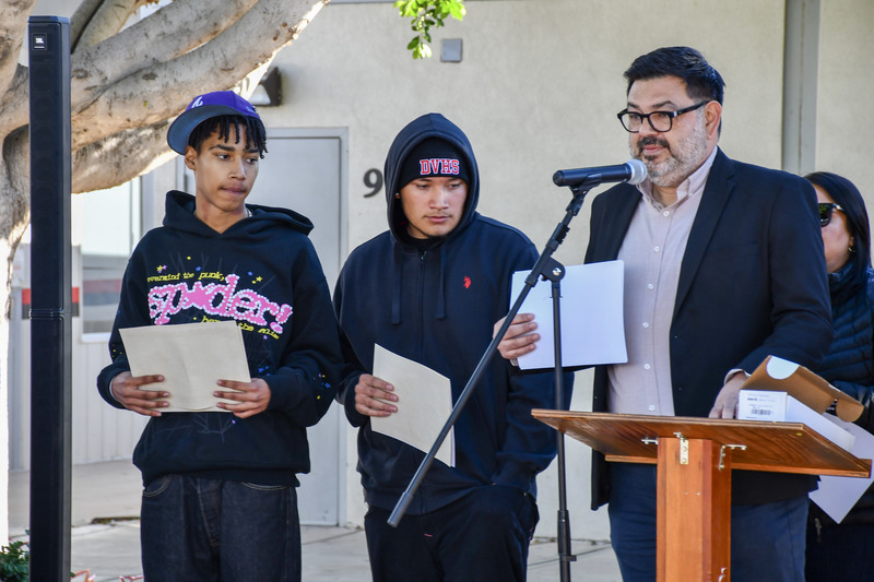 Principal Leyva announces student during awards ceremony. Two students stand next to him
