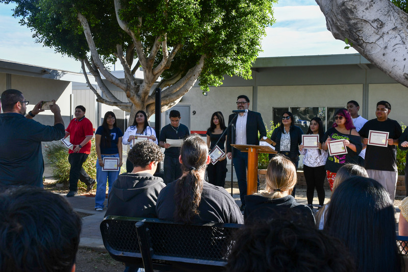 Students line up the stage holding certificates.