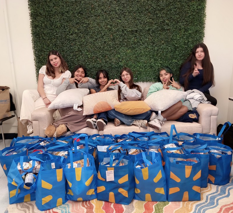Community school ambassadors pose next to bags of food for donation drive