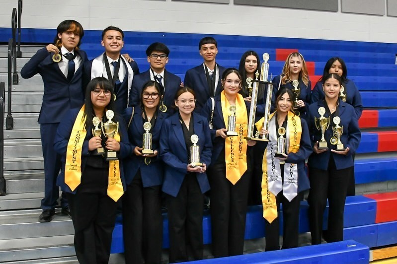 students pose for picture holding awards at speech and debate competition