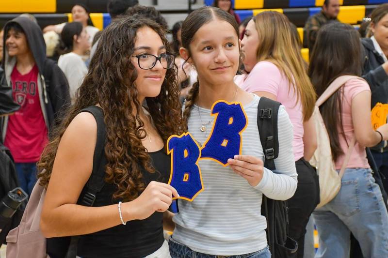 Two freshman students hold up Academic Patch of a "B" while smiling for photo.