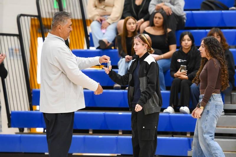 Counselor Felix shakes hand with student while handing out academic award, another student waits behind them to receive award.