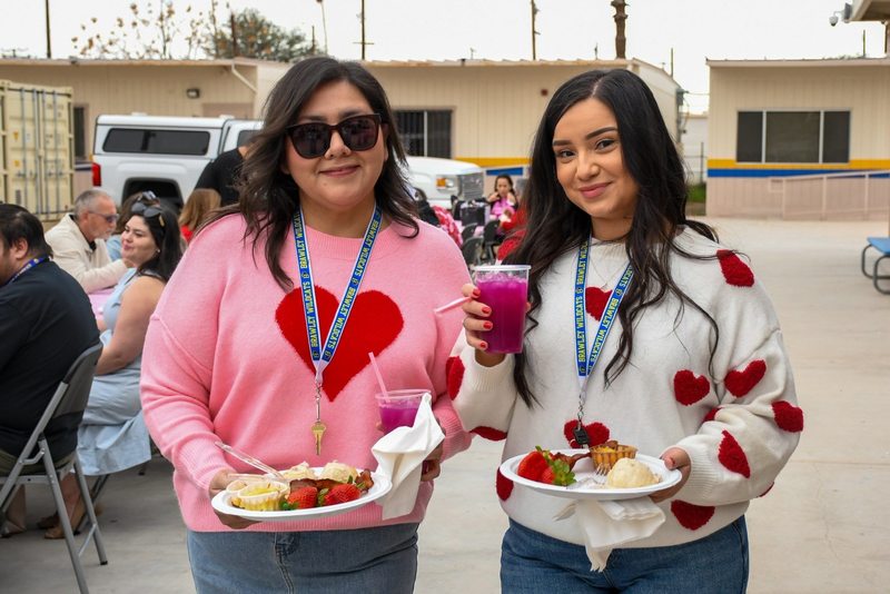 Community School Leaders Dalia and Kimberly hold up their breakfast plate and pose for photo.