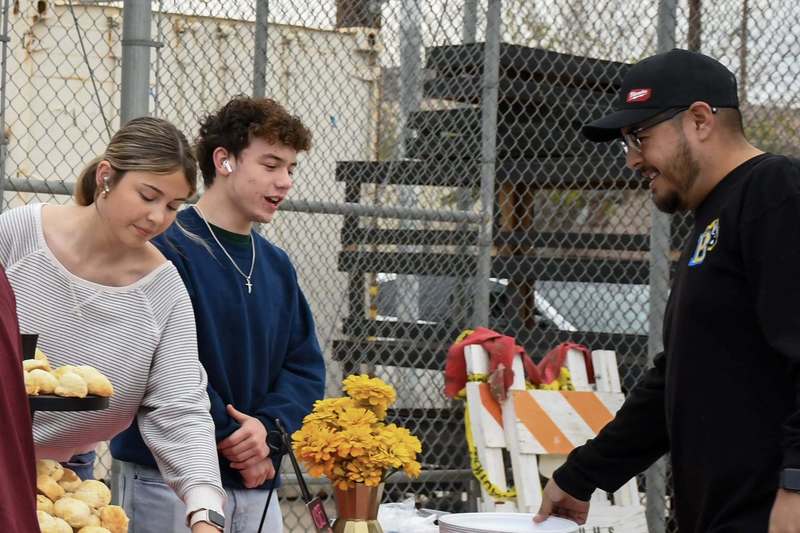 Students speak to teacher while serving food.