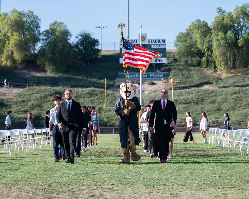 Students walking into promotion led by members of the  staff and our mascot Bosco.