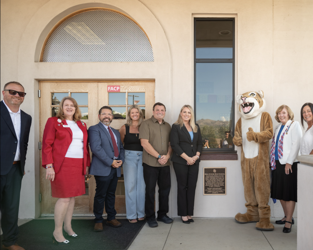 A group stands near a plaque at the entrance of Brea Junior High