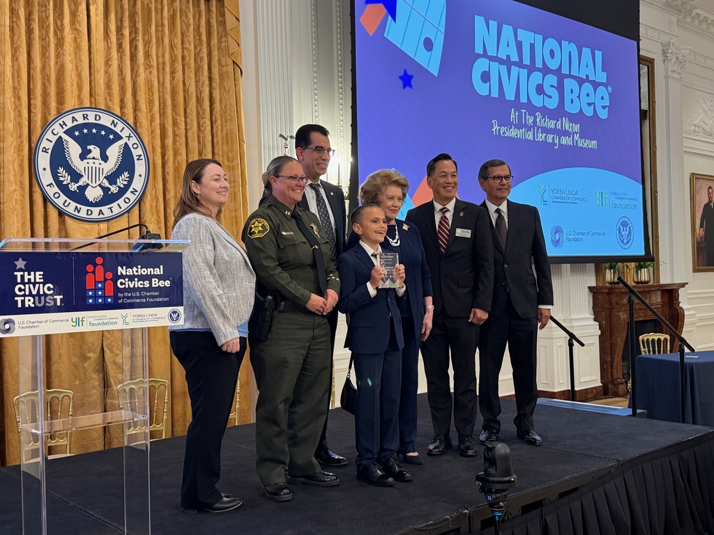 Logan stands on stage with other adults to receive the award for the National Civics Bee