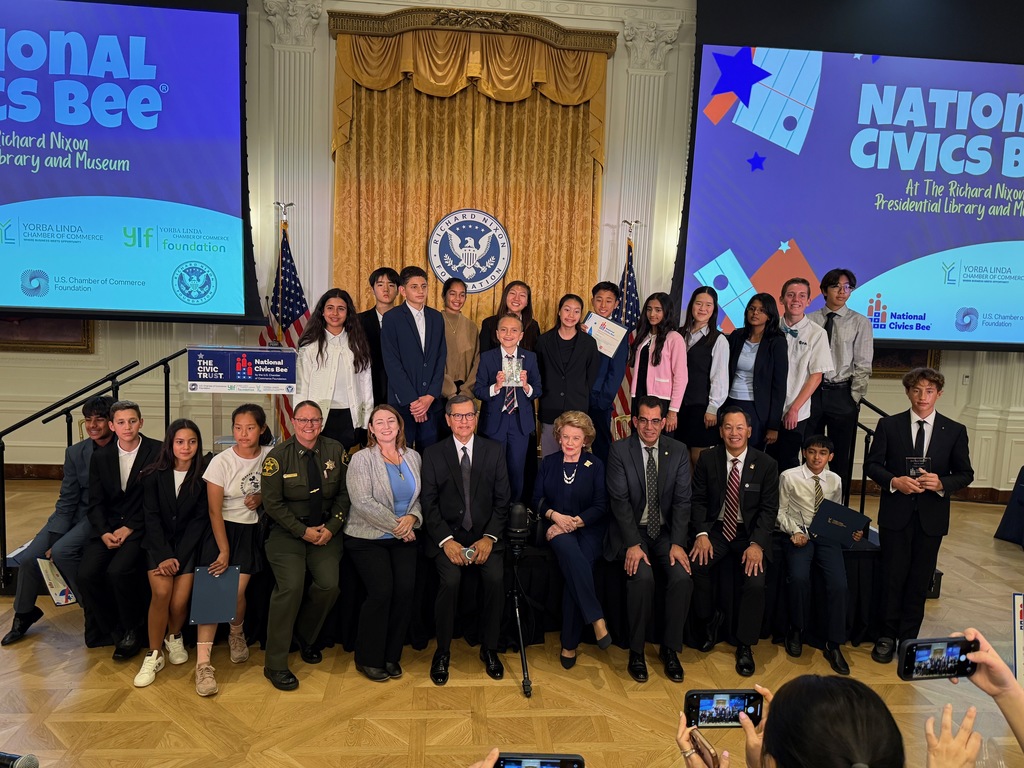 A group photo of adults and students on stage at the National Civics Bee competition