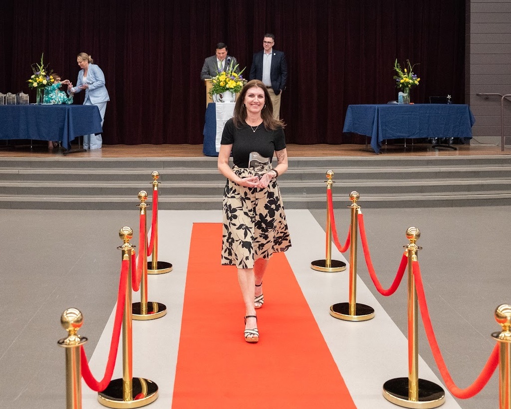 kristi rivera featured between red and gold stanchions and walking on a red carpet 