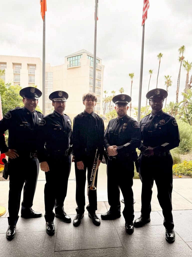 members of the brea police department in uniform stand with BOHS student Max. Flags and a building can be seen behind them