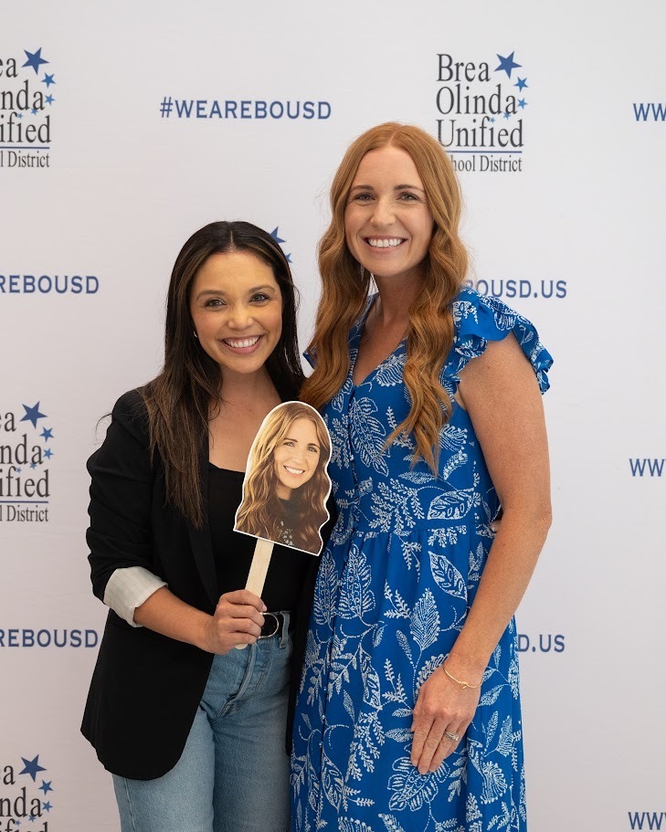 Laurel Principal Erika Lopez stands with teacher Courtney Collins in front of a step and repeat