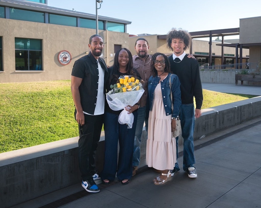 Lakisha Ozan and family stand outside of Olinda Elementary. Lakisha is holding a bouquet of yellow roses
