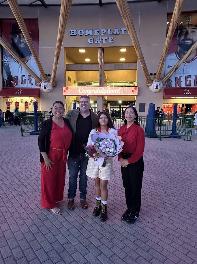 a group of Brea Junior High staff stands with Camila in front of Angel Stadium
