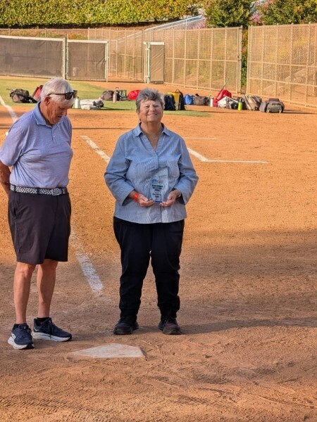 Sharen Caperton stands on the baseball field accepting her award next to another unknown gentleman
