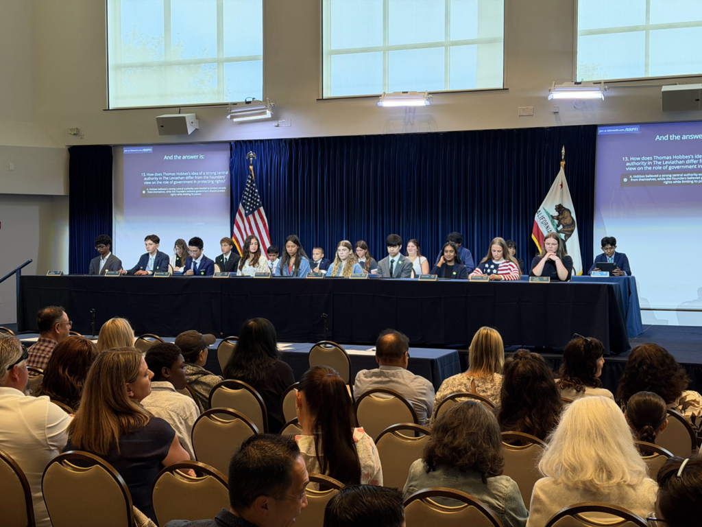 students sit on stage competition. group of adults sitting in crowd