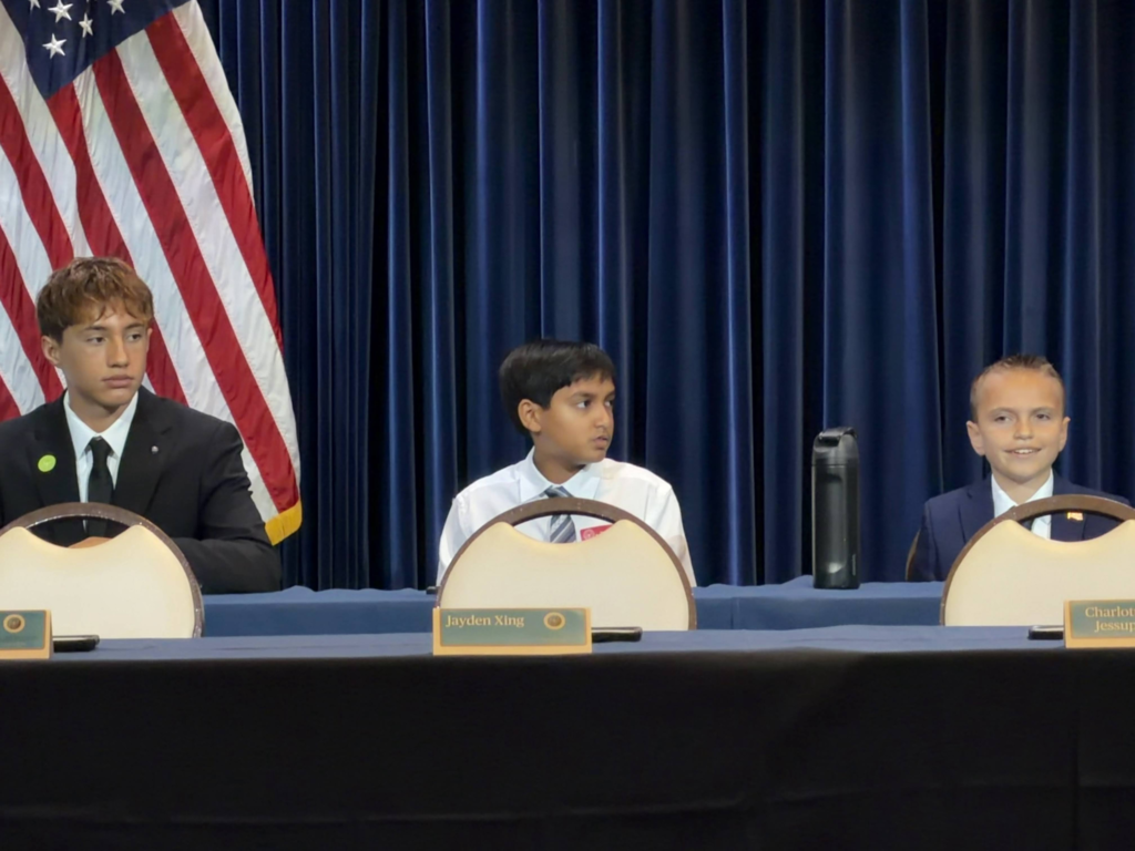 three students sit at a table at the competition